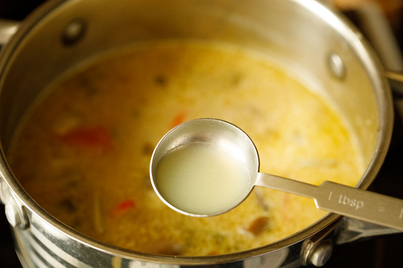 tablespoon of lemon juice above pot of tom kha soup