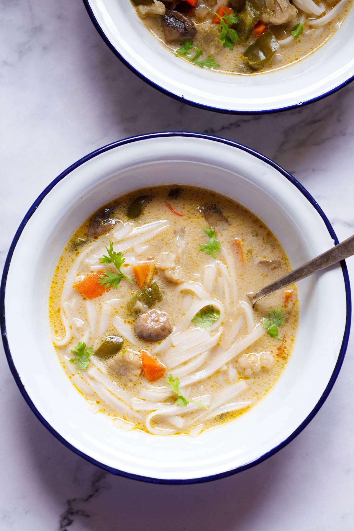 bowl of vegan tom kha soup with a silver spoon