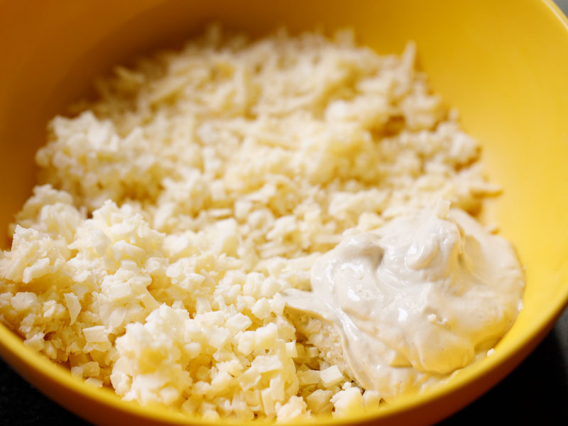 mayonnaise, cheddar and mozzarella added to a yellow mixing bowl