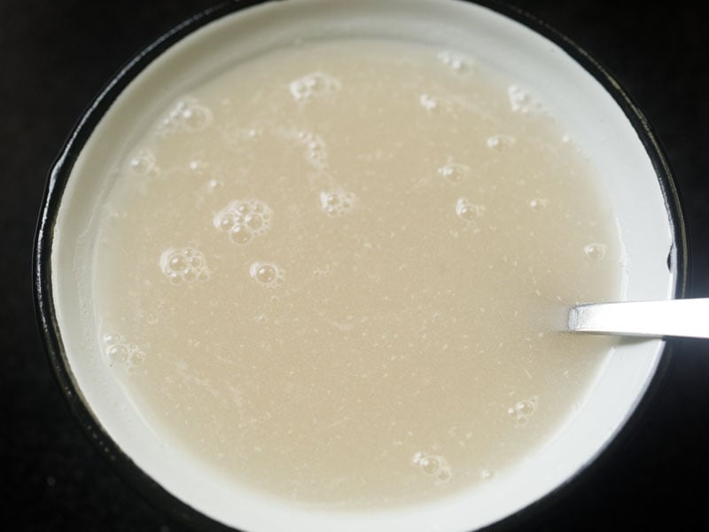 warm water mixed with the yeast and sugar with a spoon in the white bowl