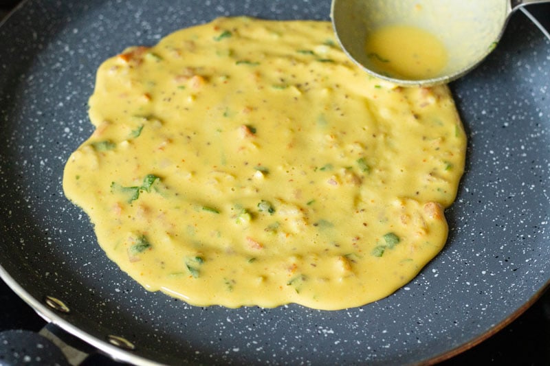 batter being spread neatly with the spoon on the skillet