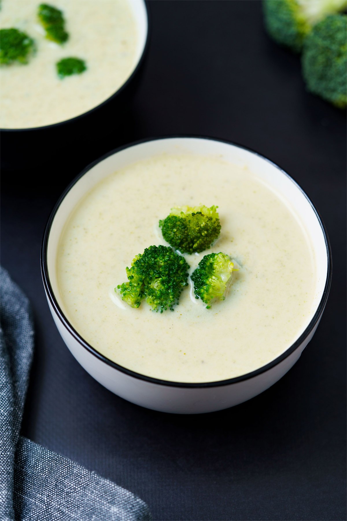 top shot of soup in white bowl topped with three small broccoli florets