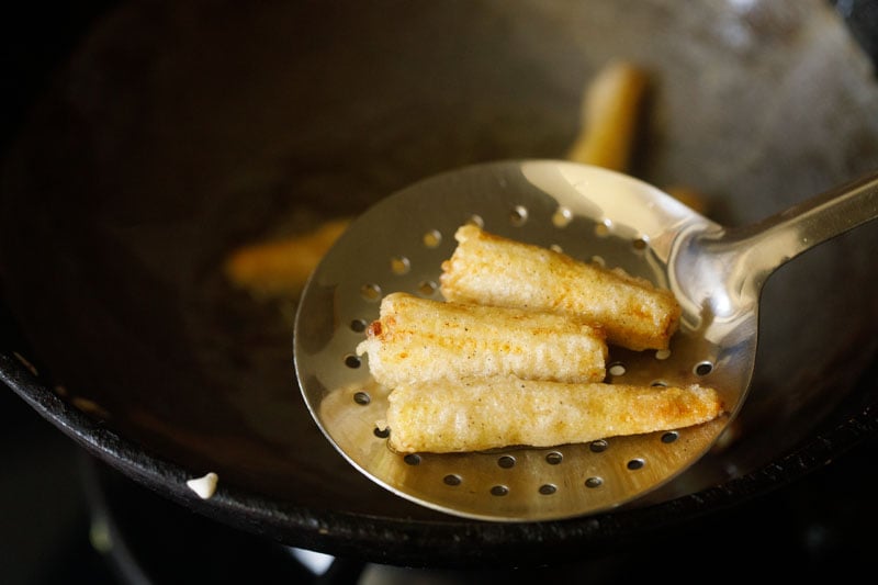 fried baby corn pieces removed with slotted spoon