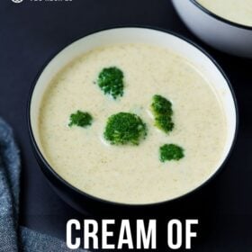 cream of broccoli soup topped with broccoli florets in a black rimmed white bowl on a black board with text layovers.