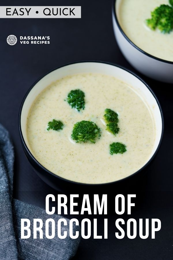cream of broccoli soup topped with broccoli florets in a black rimmed white bowl on a black board