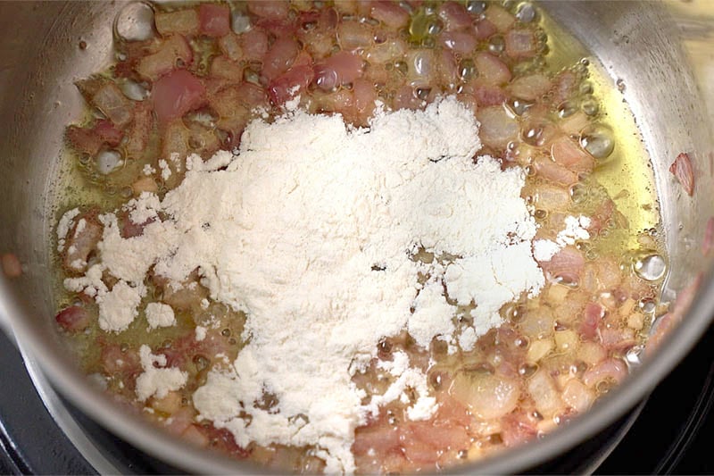 top shot of flour added to sautéed onion mixture in pot