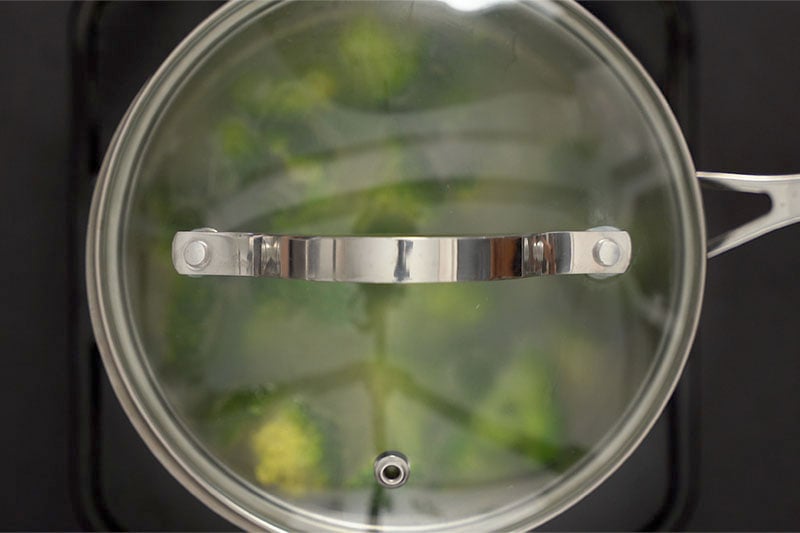 top shot of covered pot with broccoli soup cooking inside