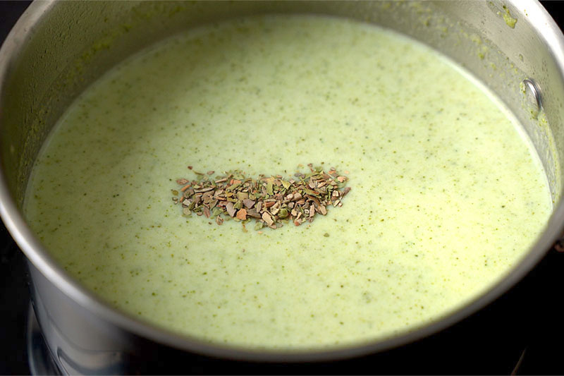 top shot of creamy broccoli soup with dried oregano added to the top in saucepan