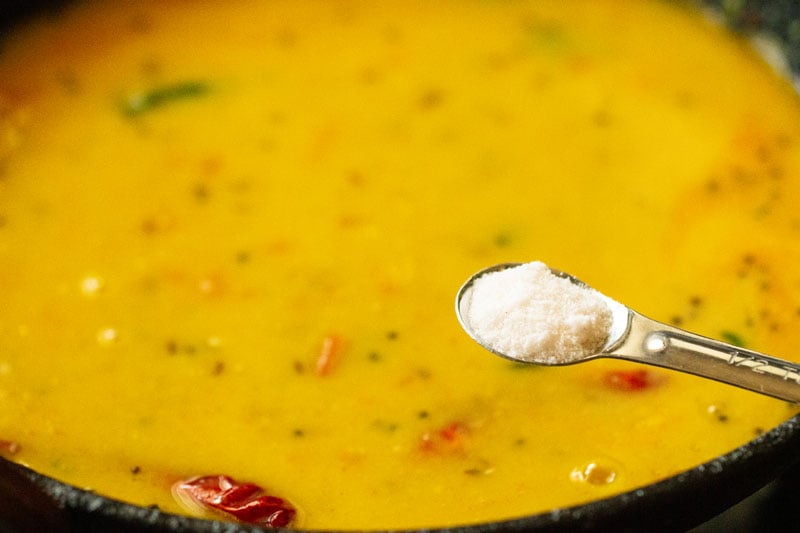 salt being added with a measuring spoon into the dal fry