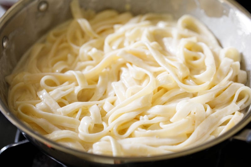 fettuccine alfredo sprinkled with seasonings in a pan