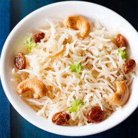 ghee rice topped with fried cashews, raisins, coriander leaves in a white bowl