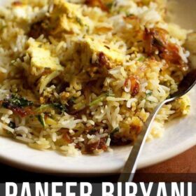 paneer biryani served on a cream shallow plate with a steel spoon by the side and text layovers.