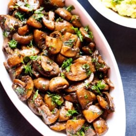 overhead shot of oblong white serving bowl filled with sautéed mushrooms and a side of guacamole