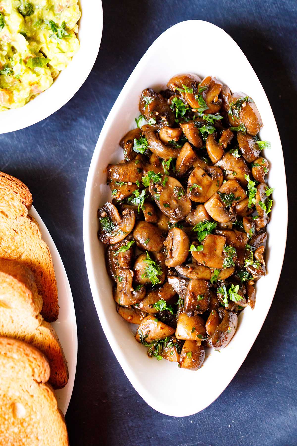 overhead shot of oblong white serving bowl filled with sautéed mushrooms and a side of guacamole for an easy lunch