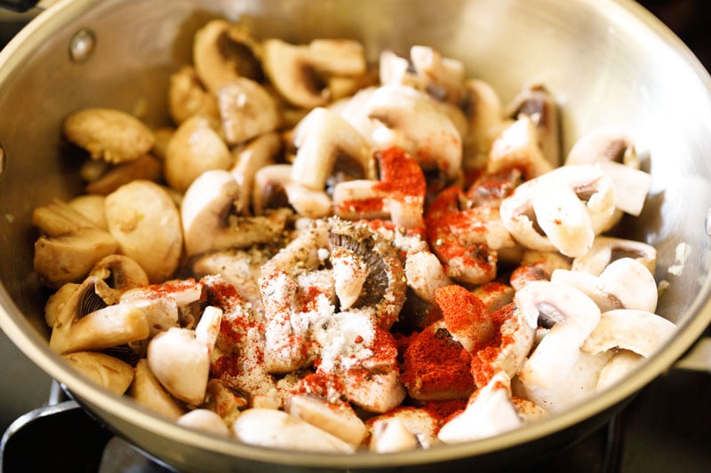pepper, paprika and salt added to mushrooms in pan