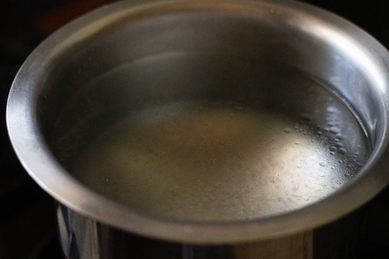 water with oil and salt being heated in a steel pan