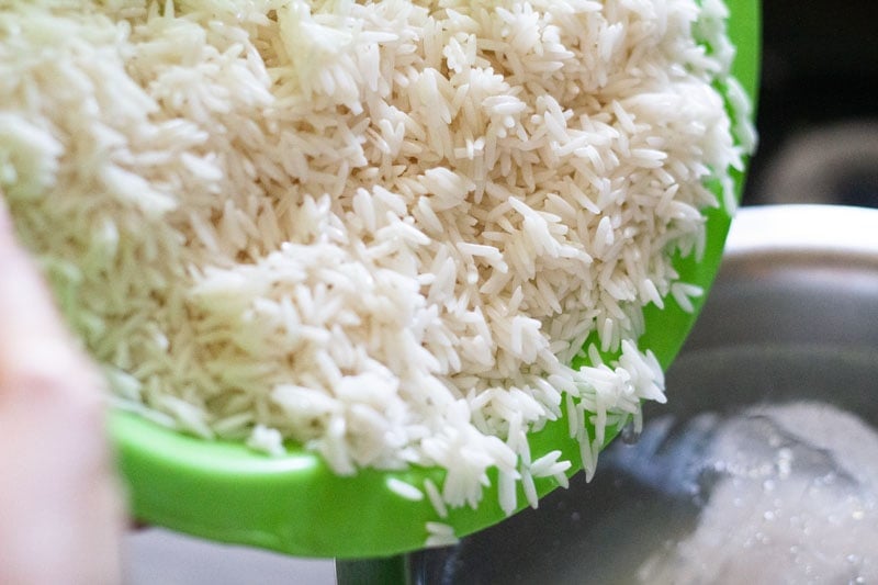 rice being added to hot water in the steel pan