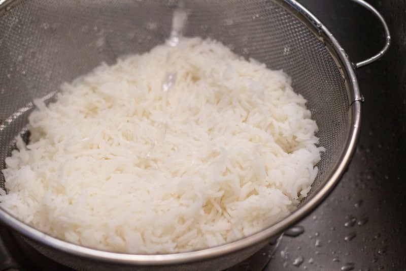rinsing cooked rice with fresh water in a colander
