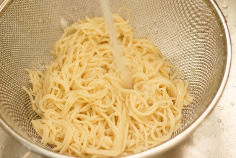 rinsing cooked noodles with fresh water in the strainer