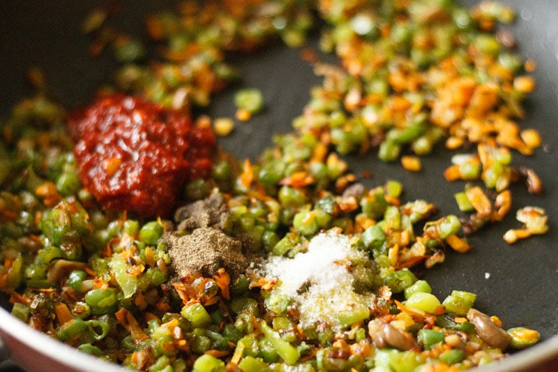 schezwan sauce, salt and black pepper in the pan on top of the stir fried vegetables