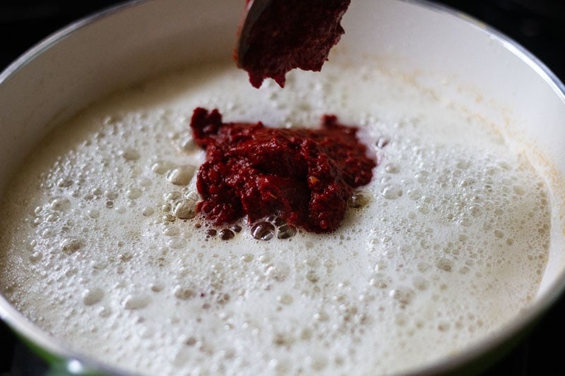 ground red chilli paste being added to hot oil