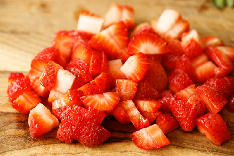 chopped strawberries on a wooden cutting board 