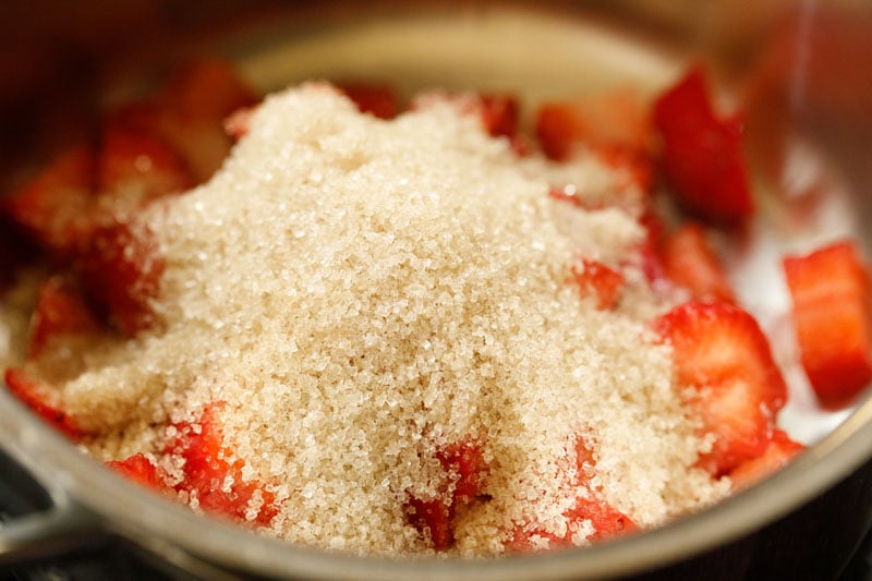 cane sugar added to saucepan with chopped fresh strawberries