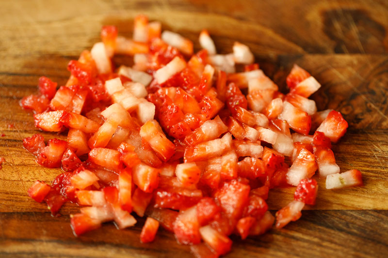 finely chopped strawberries on a wooden cutting board