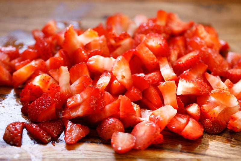chopped strawberries on a wooden chopping board