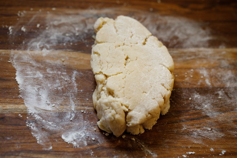 dough folded on wooden board with some flour sprinkled on board and dough