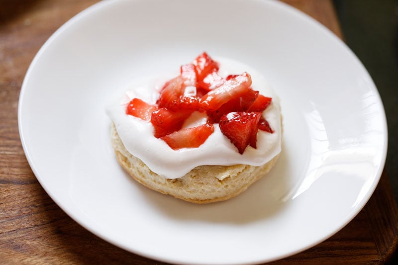 shortcake halve topped with whipped cream and macerated strawberry stuffing and juices