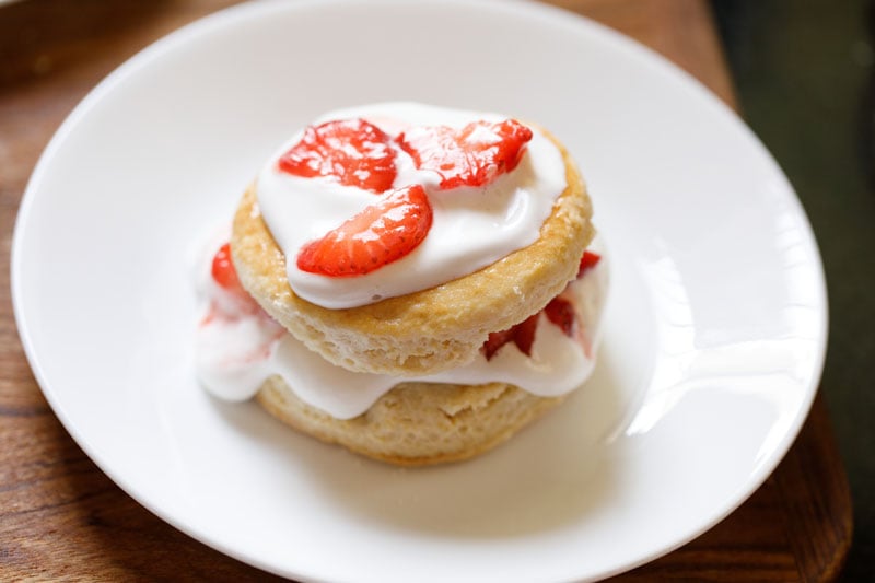 strawberry shortcake assembled and the top halve topped with cream and some strawberries