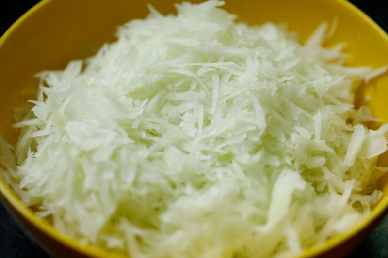 shredded green papaya in a yellow bowl