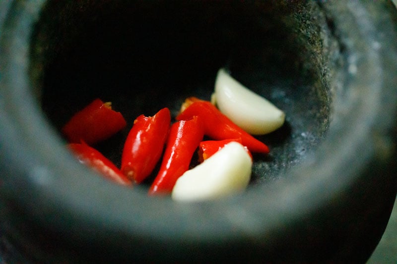 garlic cloves and bird's eye chilis in a mortar