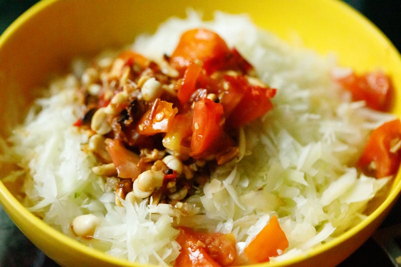 som tam dressing added to green papaya in yellow bowl