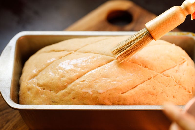 brushing atta bread loaf dough with milk.