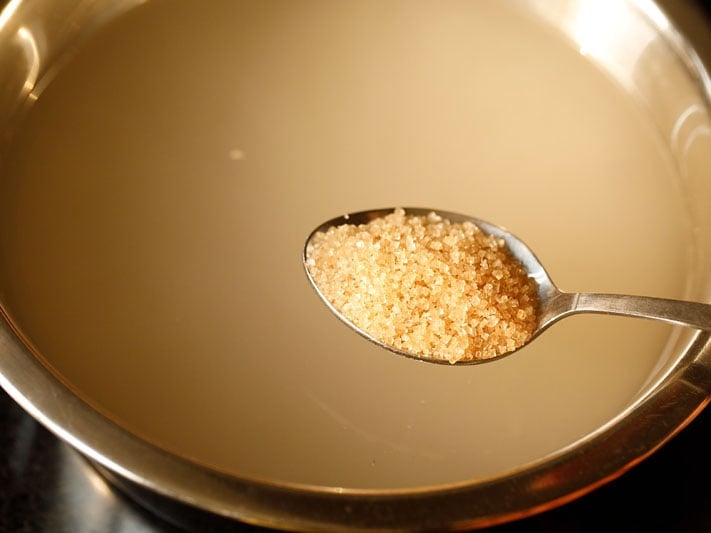 teaspoon of turbinado sugar above pot of barley water