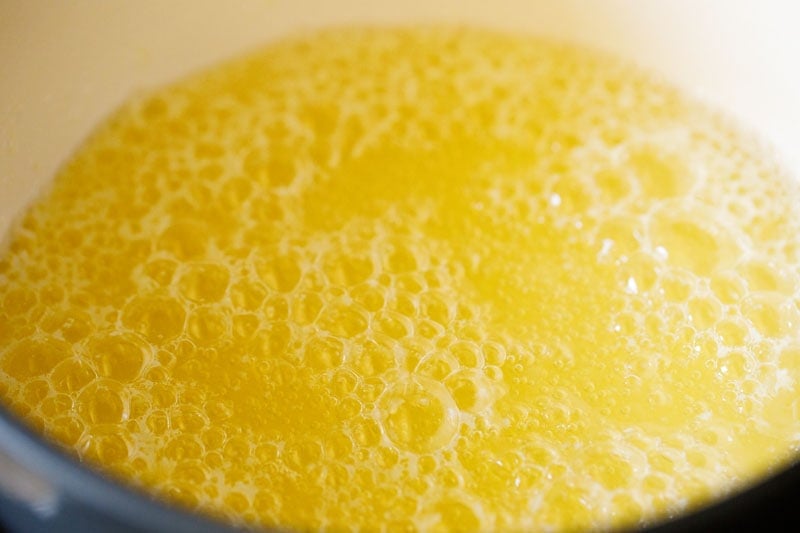 melted butter is looking darker yellow as it turns into ghee