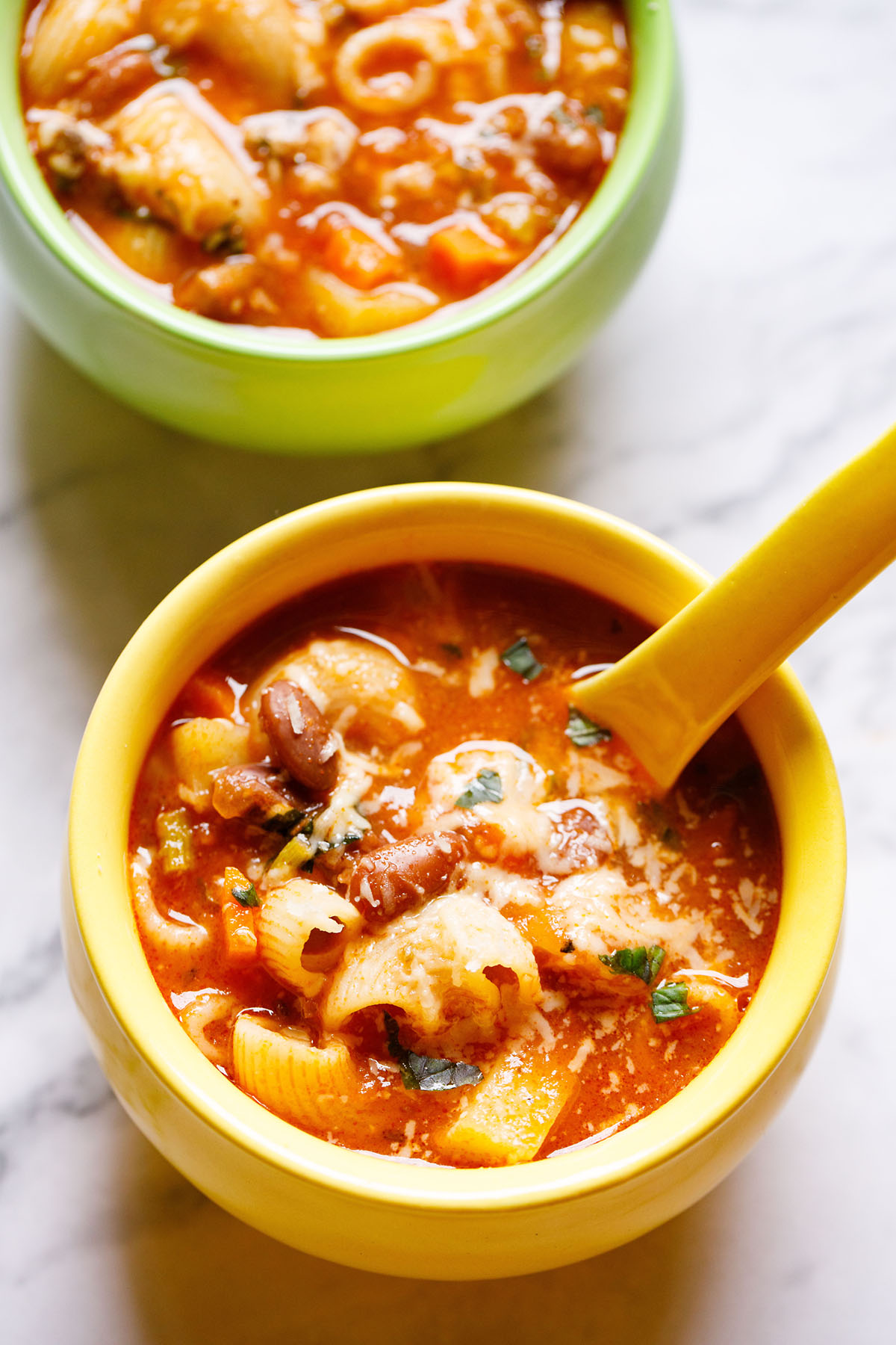 vegetarian minestrone soup in a yellow ceramic bowl with a matching spoon