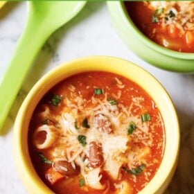 vegetarian minestrone soup in a yellow ceramic bowl with a matching spoon with an overlay of text