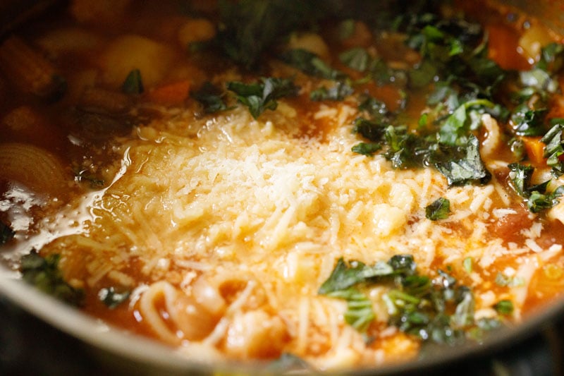 grated vegetarian parmesan and fresh basil added to stock pot with minestrone