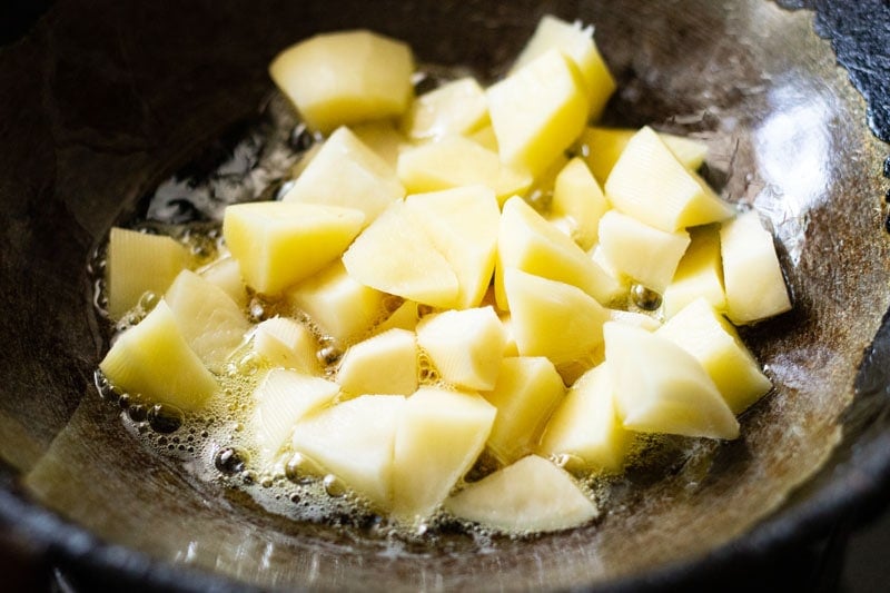 chopped potatoes in oil in a wok