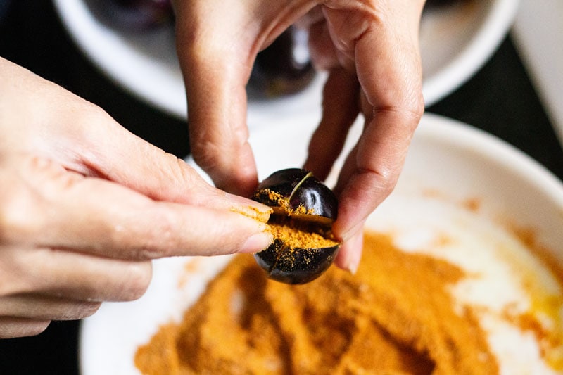 stuffing the dry spice mix in a small brinjal