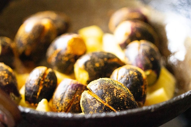 stuffed brinjals added to potatoes in wok