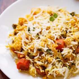 close up shot of biryani on white plate on wooden table