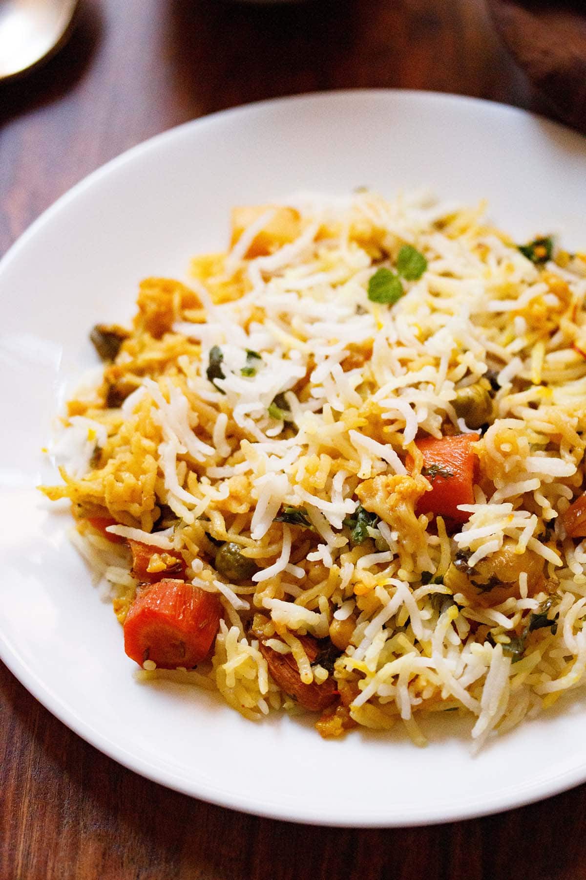 close up shot of biryani on white plate on wooden table