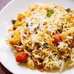 close up shot of biryani on white plate on wooden table