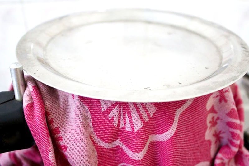 Lid sitting on pan of rice sealed with red cloth