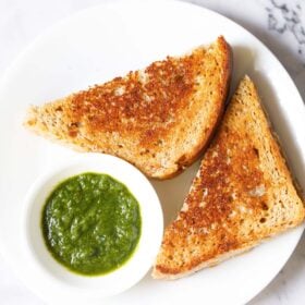 overhead shot of cheese sandwich triangle slices with cilantro dip on a white plate