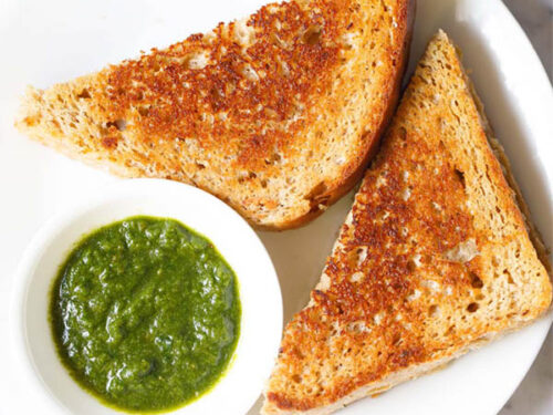 overhead shot of cheese sandwich triangle slices with cilantro dip on a white plate